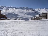 a person snow skiing down some steps in the mountains looking towards a ski lodge with an adjacent building