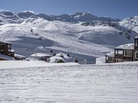 a person snow skiing down some steps in the mountains looking towards a ski lodge with an adjacent building