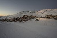 a person on skis is standing in a snowy area at sunrise by the mountains