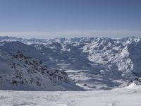 a skier on a mountain slope with a view of a valley and mountains in the background