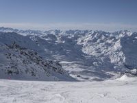 a skier on a mountain slope with a view of a valley and mountains in the background