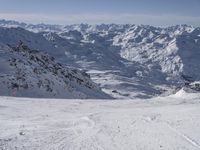 a skier on a mountain slope with a view of a valley and mountains in the background