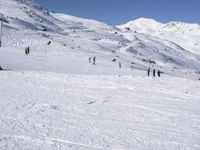 the people are all skiing in the mountains, and one person is standing near the snow