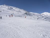 the people are all skiing in the mountains, and one person is standing near the snow