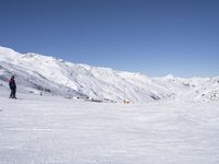 the people are all skiing in the mountains, and one person is standing near the snow