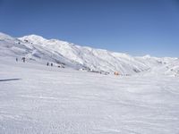 the people are all skiing in the mountains, and one person is standing near the snow