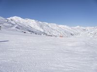 the people are all skiing in the mountains, and one person is standing near the snow