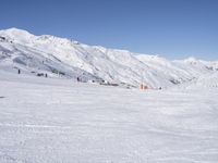 the people are all skiing in the mountains, and one person is standing near the snow