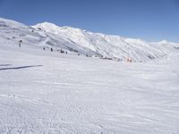 the people are all skiing in the mountains, and one person is standing near the snow