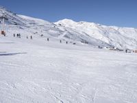 the people are all skiing in the mountains, and one person is standing near the snow