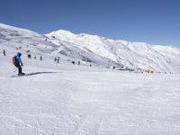 the people are all skiing in the mountains, and one person is standing near the snow