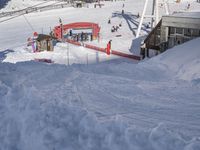 people skiing down the slopes near a red and white building at the bottom of a mountain