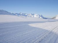 a person skiing on the snowy ground in front of snow capped mountains and blue skies