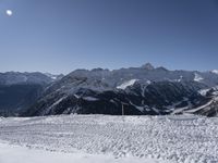 snow on the ground, mountains and skis on the slope near it, and a person in the foreground