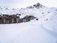 snow covered slope in the middle of a ski area as people ski on it near ski lift