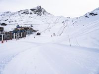 snow covered slope in the middle of a ski area as people ski on it near ski lift