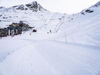 snow covered slope in the middle of a ski area as people ski on it near ski lift