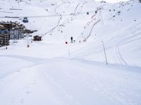 snow covered slope in the middle of a ski area as people ski on it near ski lift