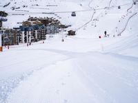 snow covered slope in the middle of a ski area as people ski on it near ski lift