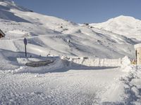 man in the snow skiing next to a building on a snowy slope, in front of a mountain