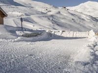 man in the snow skiing next to a building on a snowy slope, in front of a mountain