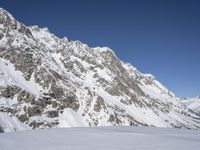 the man is standing on skis with no poles in the mountain area and looking down