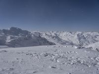 a lone skier on a snowy hill looking over the valley and snow - covered peaks