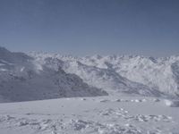 a lone skier on a snowy hill looking over the valley and snow - covered peaks