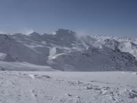 a lone skier on a snowy hill looking over the valley and snow - covered peaks