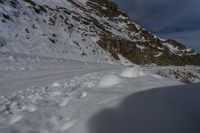 a man riding skis on a snow covered slope next to a steep cliff formation