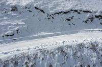 a group of people skiing up the side of a snow covered mountain slope with tracks