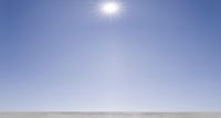 man in skis at the beach on a sunny day, with clear skies and snow