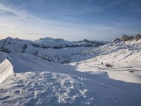 a person riding skis on top of a snow covered slope next to the mountains