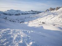 a person riding skis on top of a snow covered slope next to the mountains