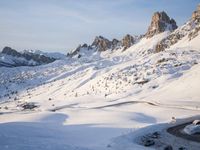 a person riding skis on top of a snow covered slope next to the mountains