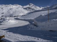 a wooden fence near a mountain covered in snow and a person skiing down the slope