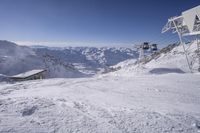 people skiing on top of a slope in front of ski lift over the mountains and snow covered ground