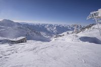 people skiing on top of a slope in front of ski lift over the mountains and snow covered ground