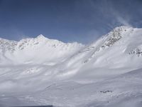 a man riding skis down the side of a snow covered slope during a sunny day