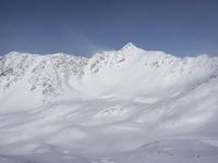 a man riding skis down the side of a snow covered slope during a sunny day