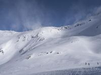 a man riding skis down the side of a snow covered slope during a sunny day