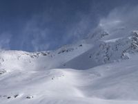 a man riding skis down the side of a snow covered slope during a sunny day