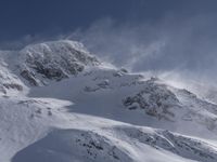 a mountain covered in snow with a skiier coming down the side of it to go through