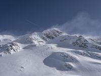 a mountain covered in snow with a skiier coming down the side of it to go through