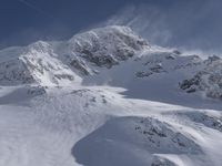 a mountain covered in snow with a skiier coming down the side of it to go through