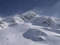 a mountain covered in snow with a skiier coming down the side of it to go through