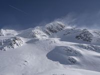 a mountain covered in snow with a skiier coming down the side of it to go through