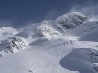 a mountain covered in snow with a skiier coming down the side of it to go through