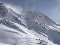 a mountain covered in snow with a skiier coming down the side of it to go through