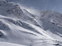 a mountain covered in snow with a skiier coming down the side of it to go through